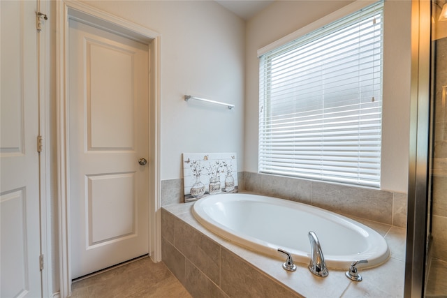 bathroom featuring a relaxing tiled tub and tile patterned flooring