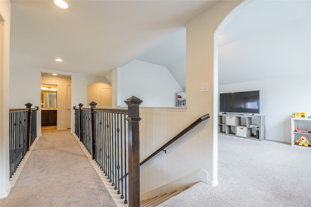 hallway featuring light carpet and vaulted ceiling