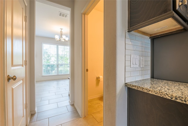 hall featuring light tile patterned flooring and a notable chandelier