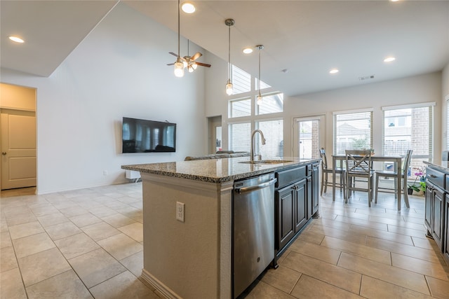 kitchen featuring sink, an island with sink, high vaulted ceiling, stainless steel dishwasher, and light stone countertops