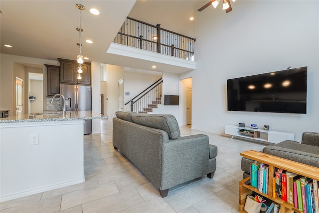 tiled living room with ceiling fan and a high ceiling