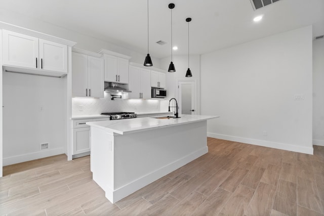 kitchen with white cabinets, sink, a kitchen island with sink, pendant lighting, and appliances with stainless steel finishes