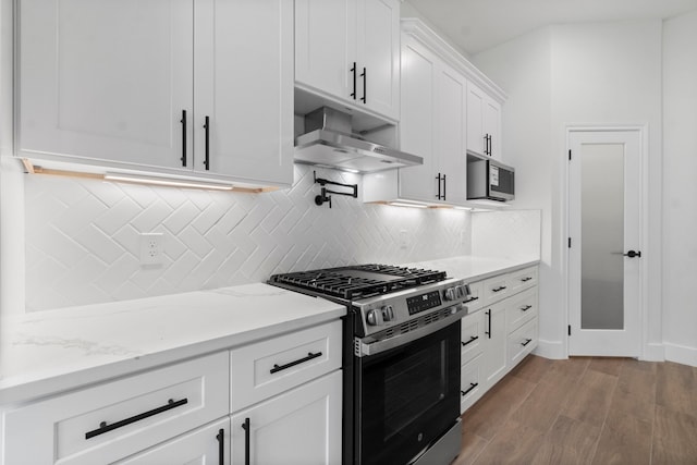 kitchen with stainless steel appliances, light hardwood / wood-style floors, light stone counters, backsplash, and white cabinets