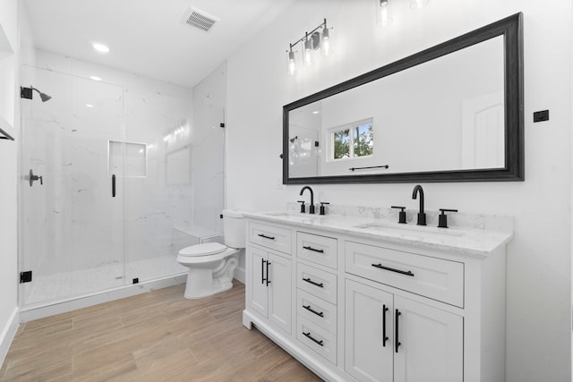 bathroom featuring wood-type flooring, toilet, vanity, and a shower with shower door