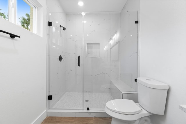 bathroom featuring toilet, wood-type flooring, and a shower with door