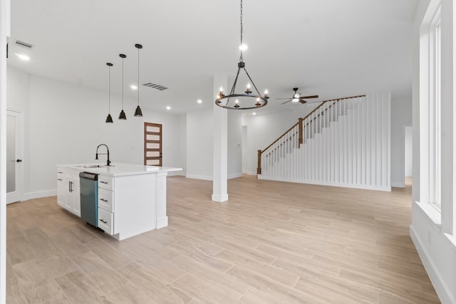 kitchen with a center island with sink, white cabinetry, pendant lighting, sink, and stainless steel dishwasher