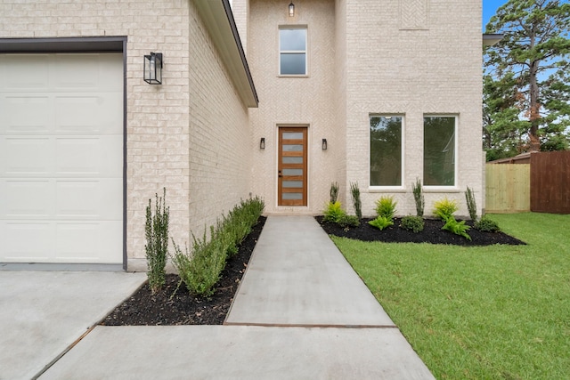 view of exterior entry with a garage and a lawn