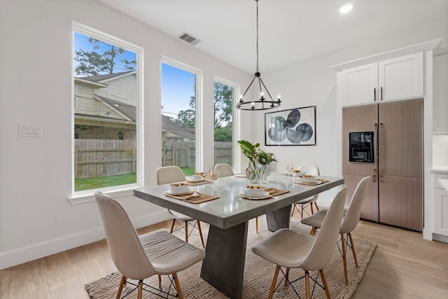 dining room with light hardwood / wood-style flooring and an inviting chandelier