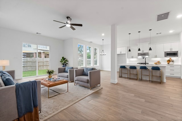 living room with a wealth of natural light, light hardwood / wood-style floors, and ceiling fan