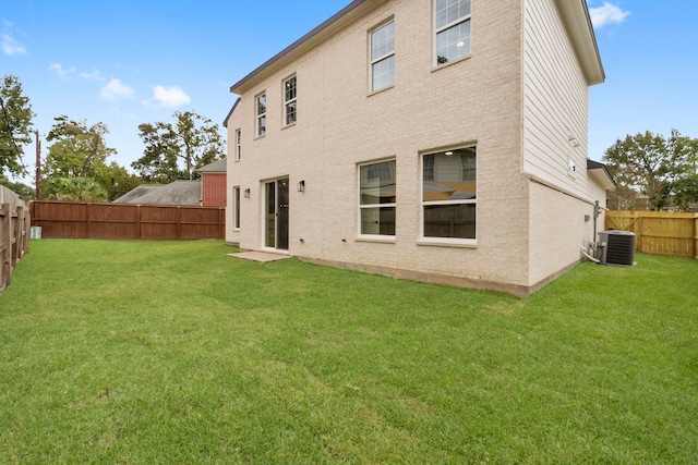 back of house featuring central air condition unit and a lawn