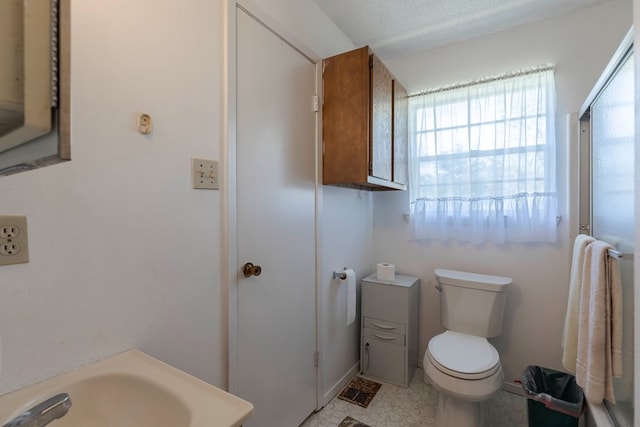 bathroom with a textured ceiling, toilet, and sink