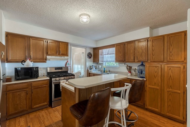 kitchen with a kitchen island, light wood-type flooring, gas range, and a breakfast bar