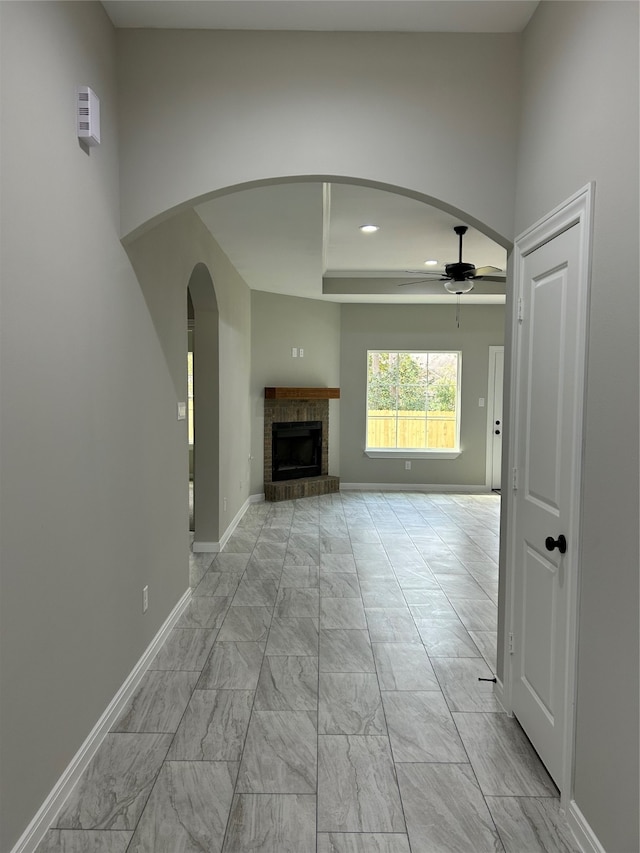 unfurnished living room with a brick fireplace and ceiling fan