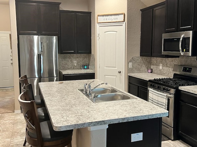 kitchen featuring a kitchen island with sink, appliances with stainless steel finishes, sink, and tasteful backsplash