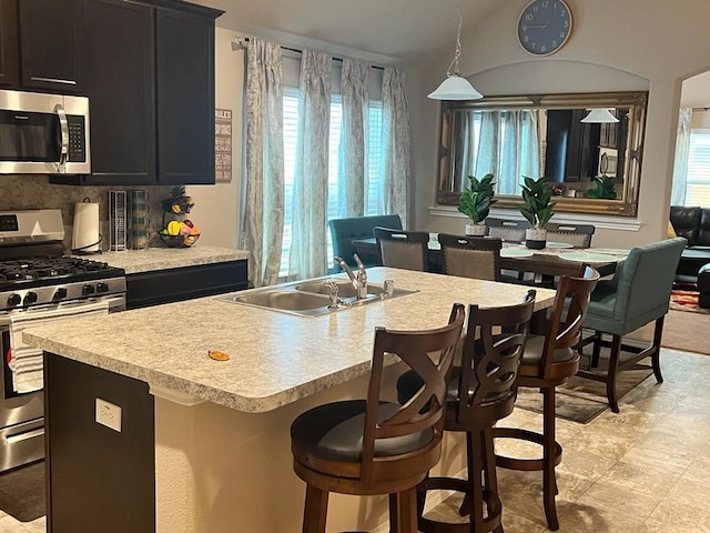 kitchen with a kitchen island with sink, pendant lighting, sink, and stainless steel appliances