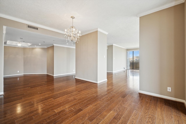 unfurnished room with hardwood / wood-style flooring, a textured ceiling, a notable chandelier, and ornamental molding