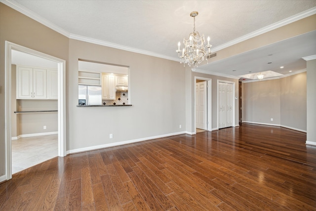 unfurnished room featuring hardwood / wood-style floors, a chandelier, and crown molding