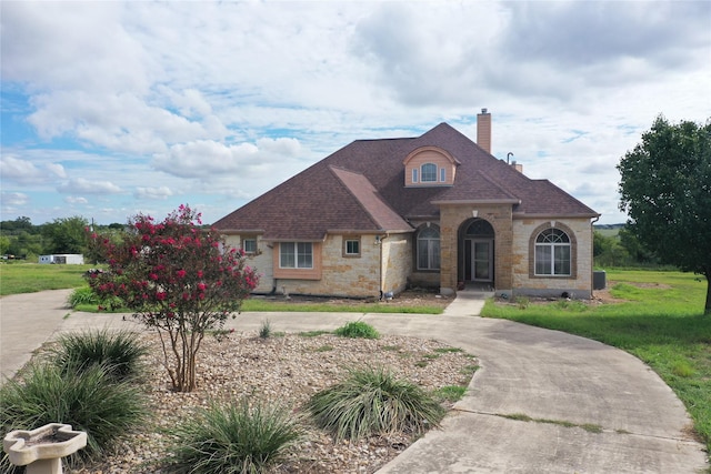 6016 Fm 2720, Maxwell, TX 78656 - view of front of home with a chimney, stone siding, a shingled roof, a front lawn, and curved driveway