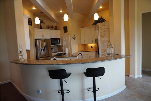 kitchen featuring tasteful backsplash, white cabinetry, appliances with stainless steel finishes, a breakfast bar area, and kitchen peninsula