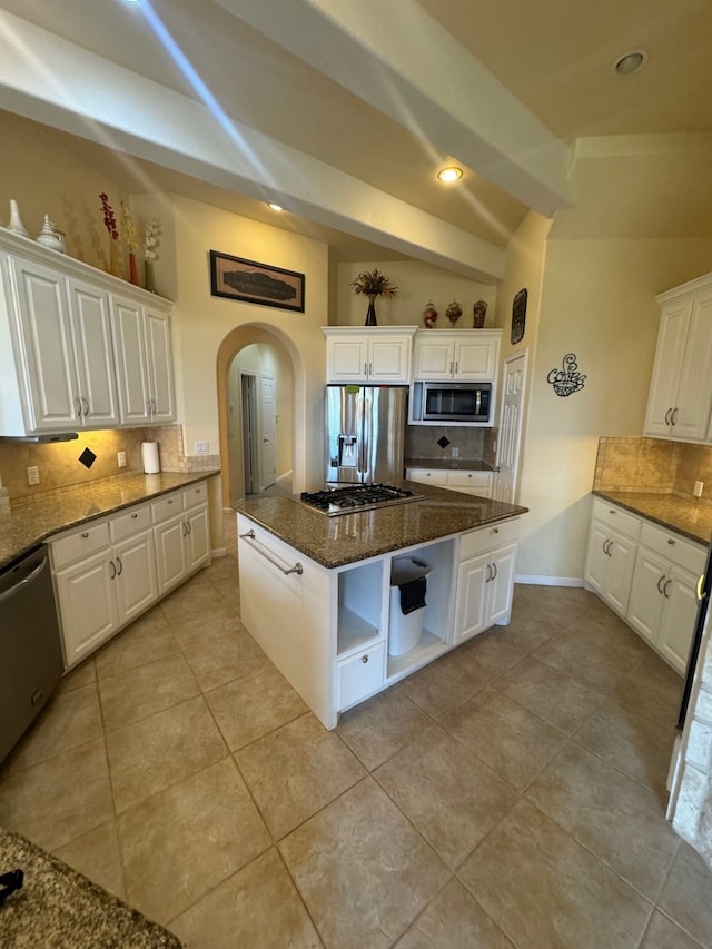 kitchen with stainless steel appliances, white cabinetry, lofted ceiling, and a center island