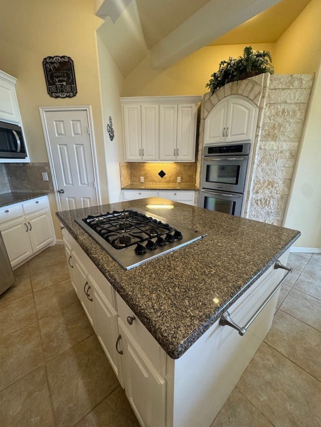 kitchen with stainless steel appliances, lofted ceiling, tasteful backsplash, a kitchen island, and white cabinetry