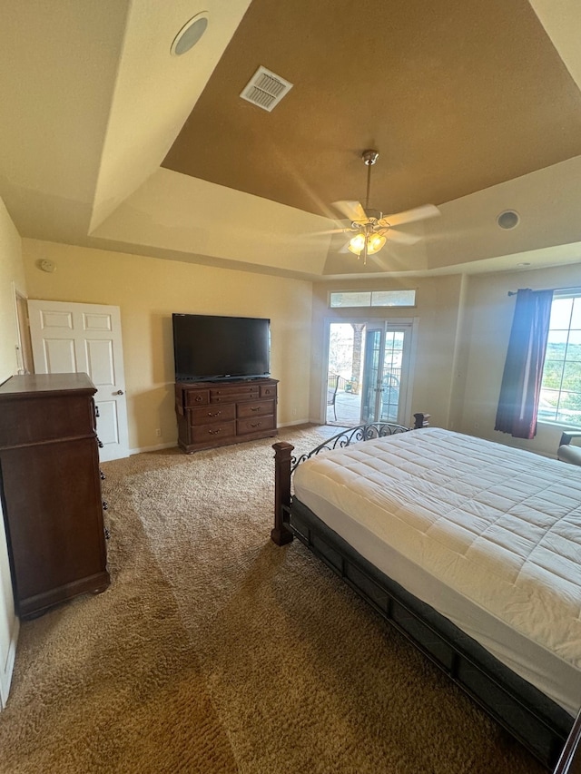 carpeted bedroom featuring ceiling fan and a tray ceiling