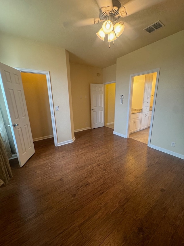 unfurnished bedroom with ensuite bathroom, ceiling fan, a closet, and wood-type flooring