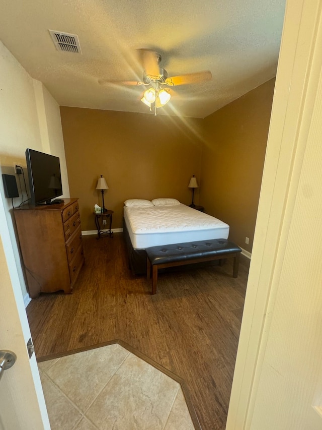 bedroom featuring ceiling fan, a textured ceiling, and wood-type flooring