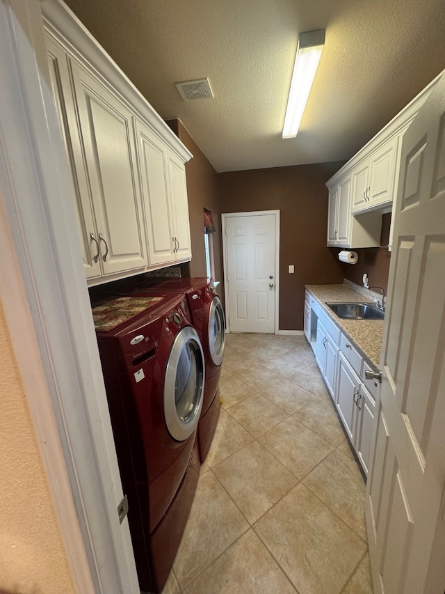 laundry area featuring cabinets, a textured ceiling, sink, washing machine and clothes dryer, and light tile patterned flooring