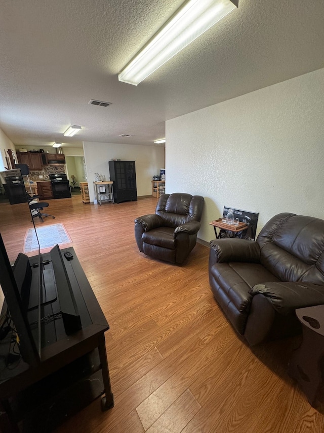 living room with a textured ceiling and light hardwood / wood-style flooring