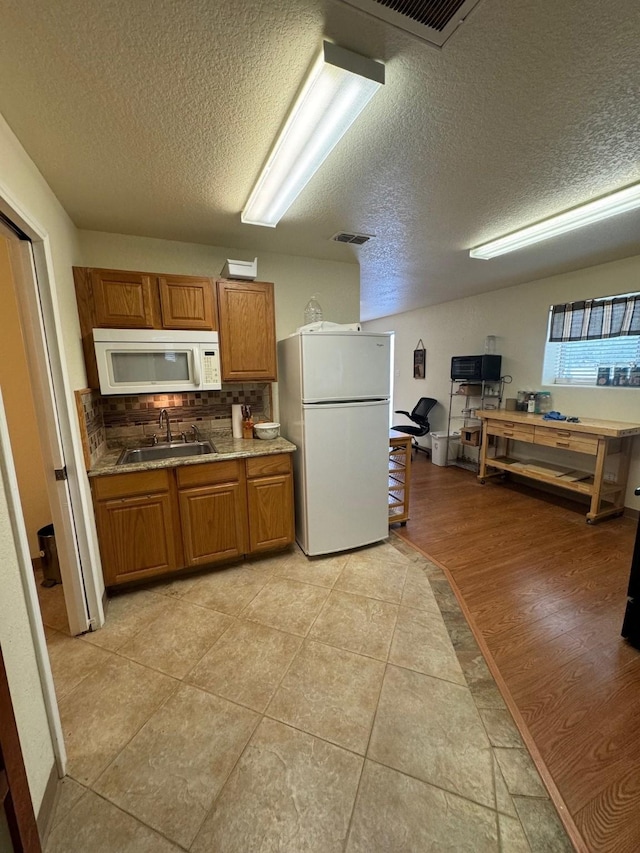 6016 Fm 2720, Maxwell, TX 78656 - kitchen with white appliances, a textured ceiling, brown cabinets, a sink, and tasteful backsplash
