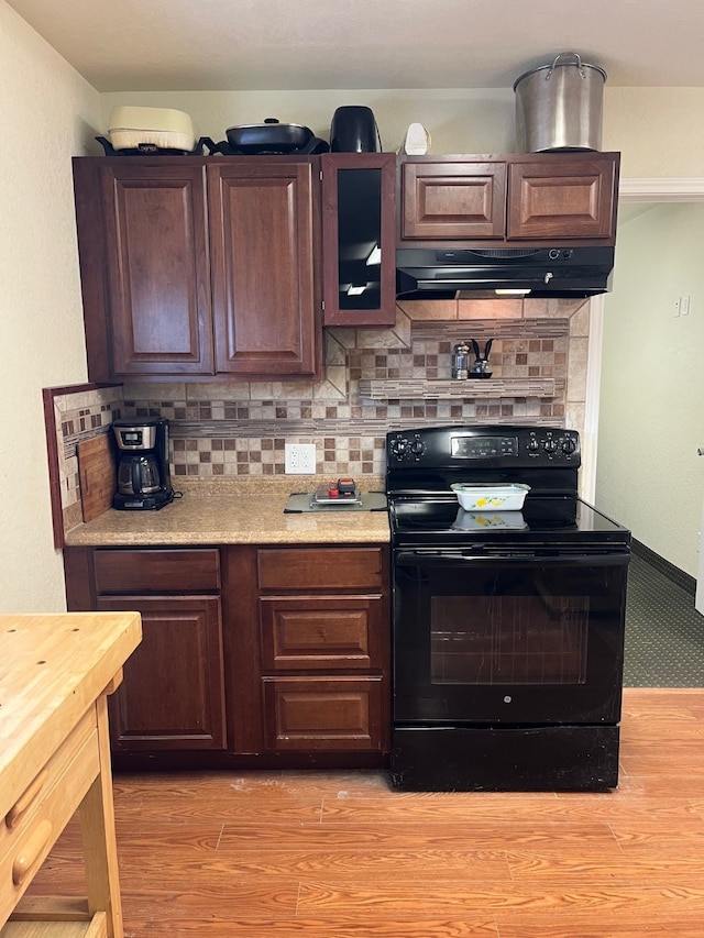 kitchen with dark brown cabinets, black electric range oven, decorative backsplash, and light hardwood / wood-style floors