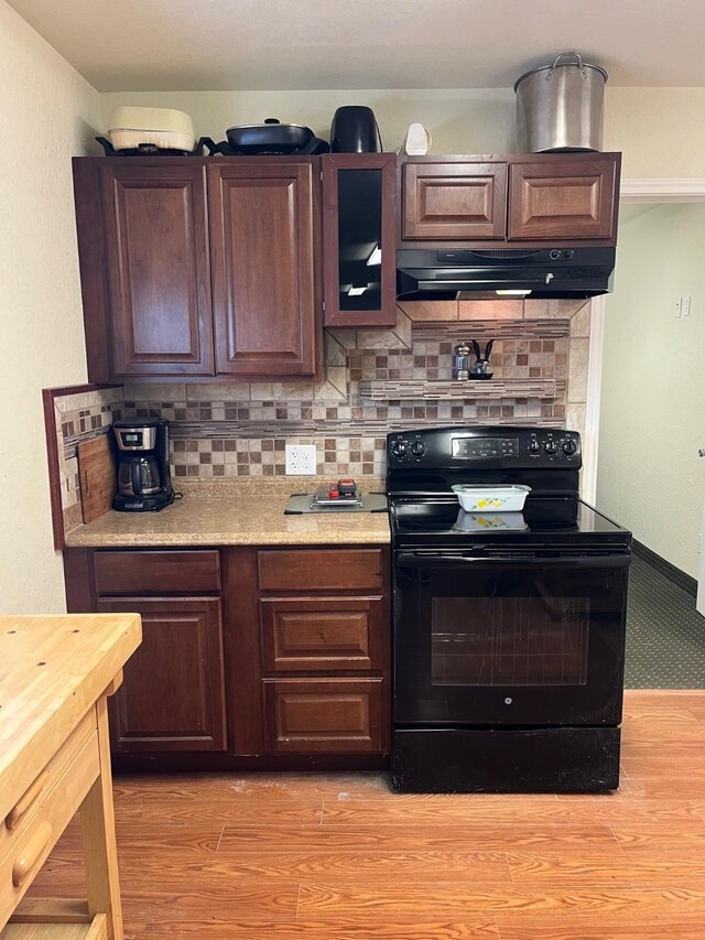 6016 Fm 2720, Maxwell, TX 78656 - kitchen featuring black range with electric stovetop, under cabinet range hood, tasteful backsplash, and light wood-style flooring