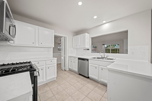 kitchen featuring stainless steel appliances, light stone counters, white cabinets, sink, and light tile patterned floors