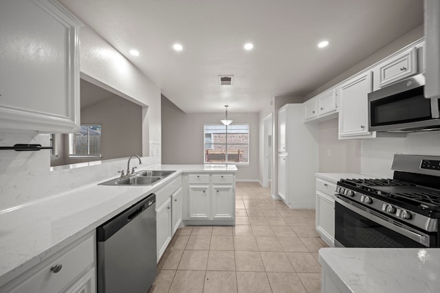 kitchen with white cabinets, kitchen peninsula, stainless steel appliances, and light stone counters