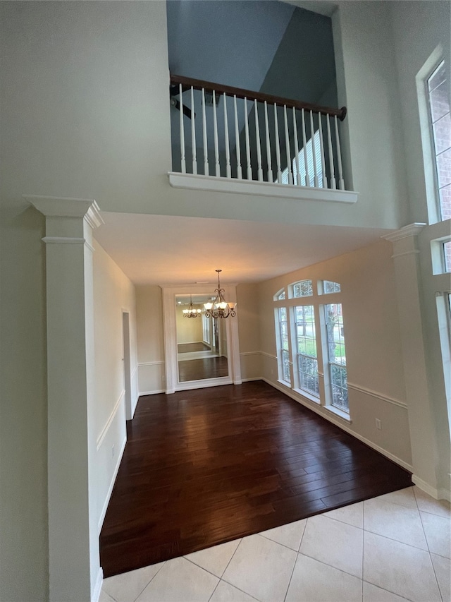 unfurnished living room with ornate columns, light hardwood / wood-style floors, and a chandelier