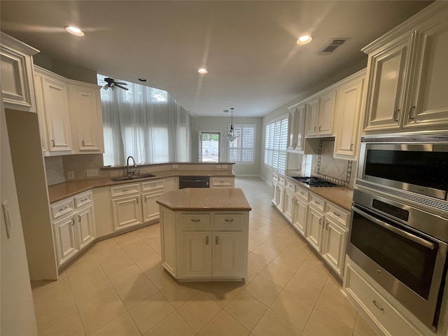 kitchen featuring sink, appliances with stainless steel finishes, ceiling fan, a center island, and pendant lighting