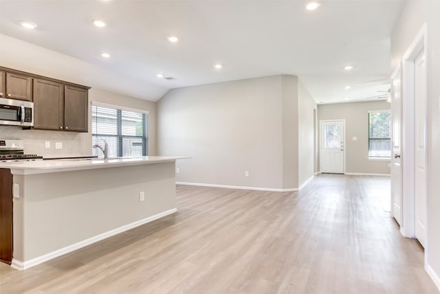 kitchen with electric range oven, ceiling fan, light hardwood / wood-style flooring, and lofted ceiling