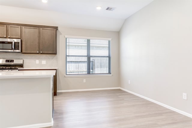 kitchen with light hardwood / wood-style flooring, backsplash, lofted ceiling, and stainless steel appliances