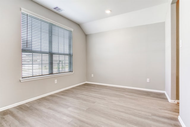 spare room with light hardwood / wood-style floors and vaulted ceiling