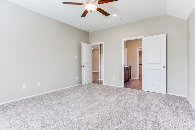 unfurnished bedroom with ensuite bathroom, lofted ceiling, ceiling fan, and carpet floors