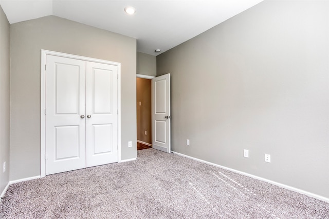 unfurnished bedroom featuring light carpet, a closet, and lofted ceiling