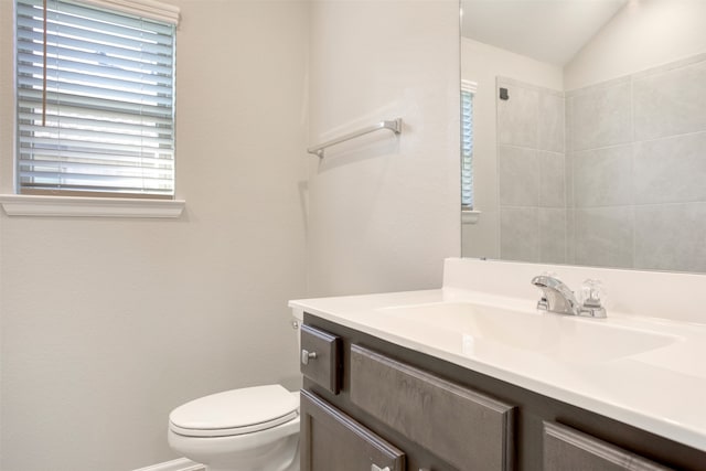 bathroom featuring vanity, a healthy amount of sunlight, toilet, and vaulted ceiling