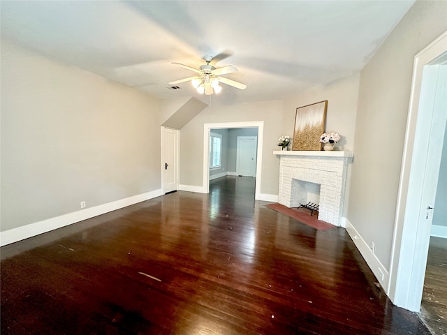 unfurnished living room with dark wood-type flooring, ceiling fan, and a brick fireplace