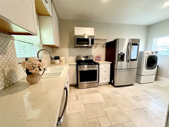 kitchen with white cabinets, sink, tasteful backsplash, appliances with stainless steel finishes, and washer / dryer