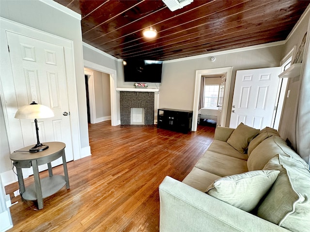 living room with a brick fireplace, hardwood / wood-style floors, ornamental molding, and wooden ceiling