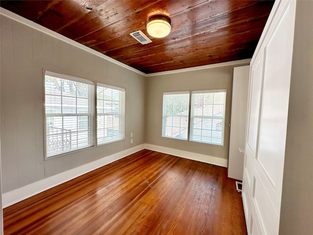 empty room featuring dark hardwood / wood-style flooring, crown molding, and wooden ceiling