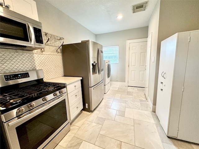 kitchen with washer and clothes dryer, backsplash, white cabinets, and stainless steel appliances