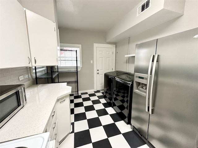 kitchen with white cabinetry, light stone counters, appliances with stainless steel finishes, washer and dryer, and decorative backsplash