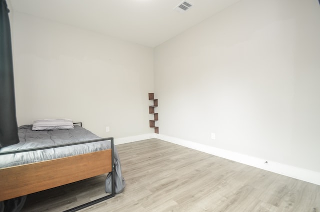 bedroom with light hardwood / wood-style floors and lofted ceiling